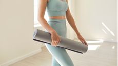 Woman in blue workout clothes with yoga mat