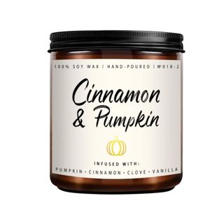 A dark brown candle jar with a beige label that says 'cinnamon and pumpkin' on it in black writing