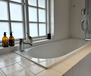 white built-in bath with tiled surround and casement window