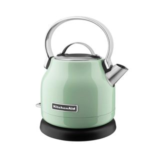 A pistachio green electric kettle with a silver handle and spout, standing on a black base