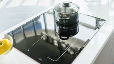 Gleaming electric stove top with pan, shot from above, and bowl of lemons to the side