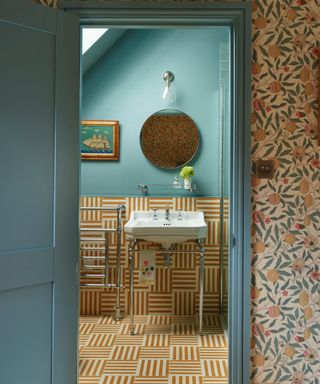 bathroom backsplash ideas, teal bathroom with yellow and white striped floor tiles that go halfway up the wall, round mirror, view of wallpaper outside bathroom