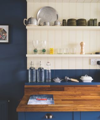 blue kitchen cabinets and matching wall, white painted tongue and groove backsplash, wooden countertop, open shelving,